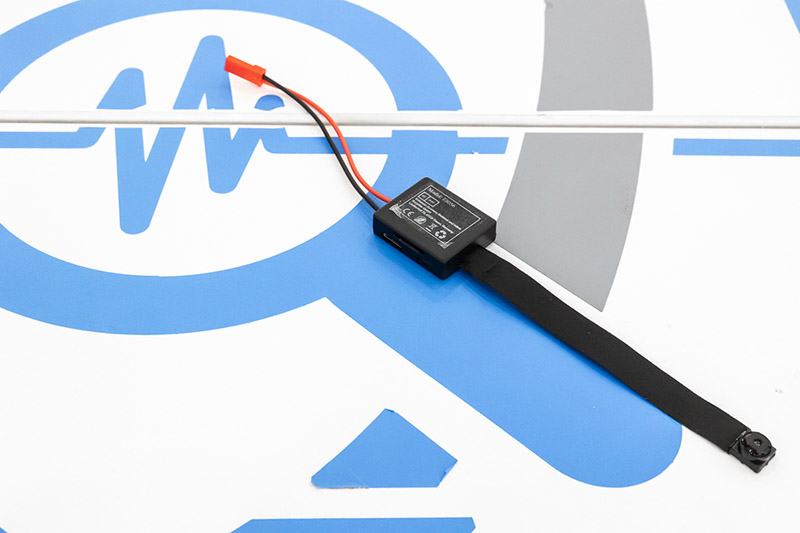Una mini telecamera spia Doctorspy con ottica flat e cavo di connessione alla corrente