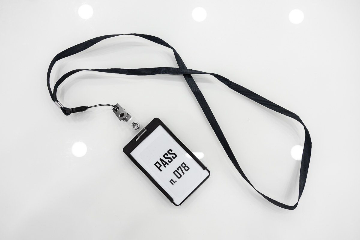 Registratore spia occultato in porta badge anonimo con cordino nero disteso su superficie bianca REC.02